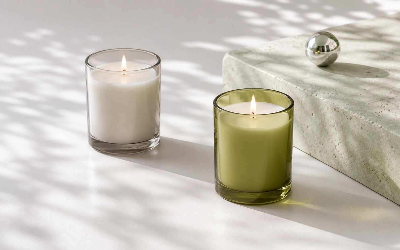 Two unlabelled candles in clear and olive glass on a mineral set