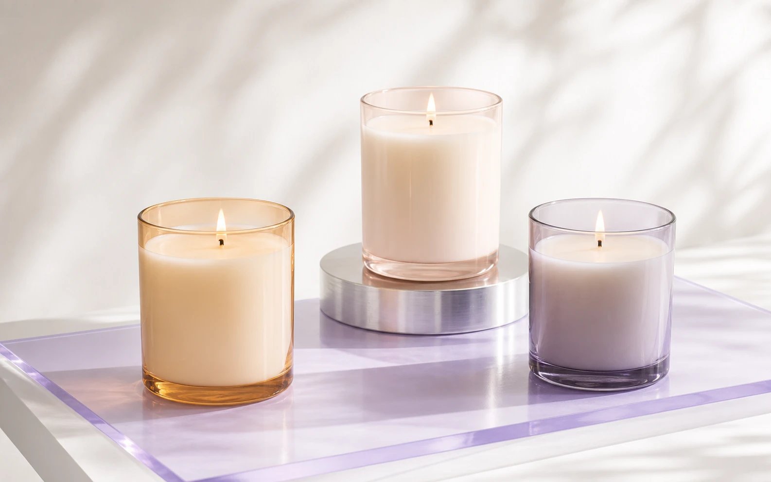Three unlabelled candles in amber, blush, and smoky violet glass